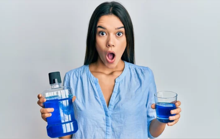 a woman holding a bottle of blue mouthwash