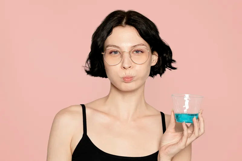 a woman holding a glass with mouthwash