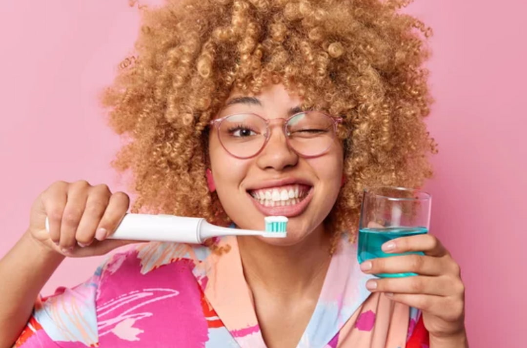 a woman holding toothbrush and mouthwash in her hands