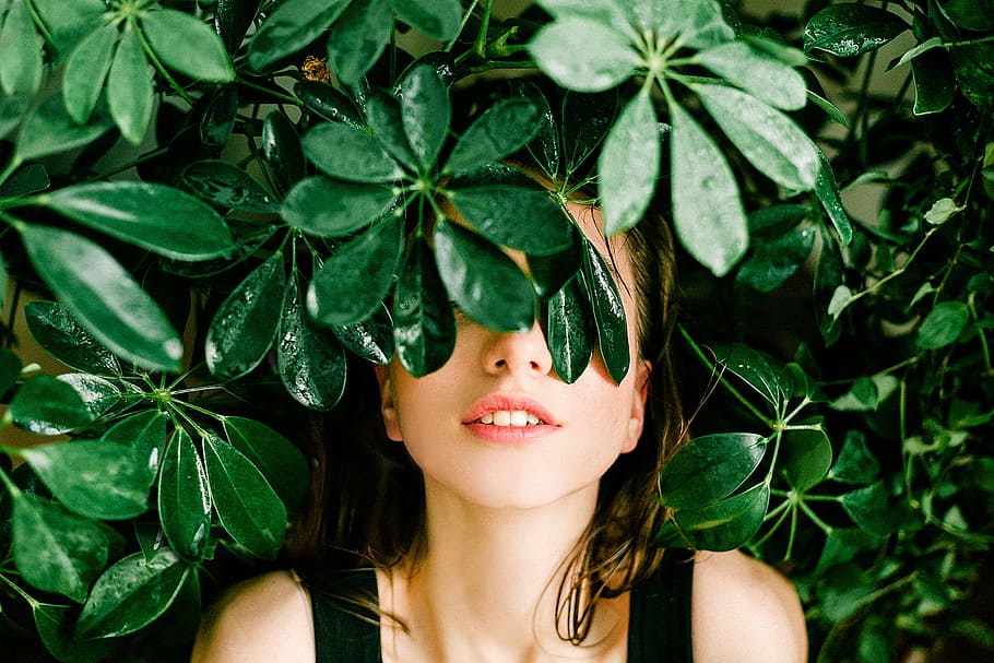 a woman in the nature with half her face covered with leaves