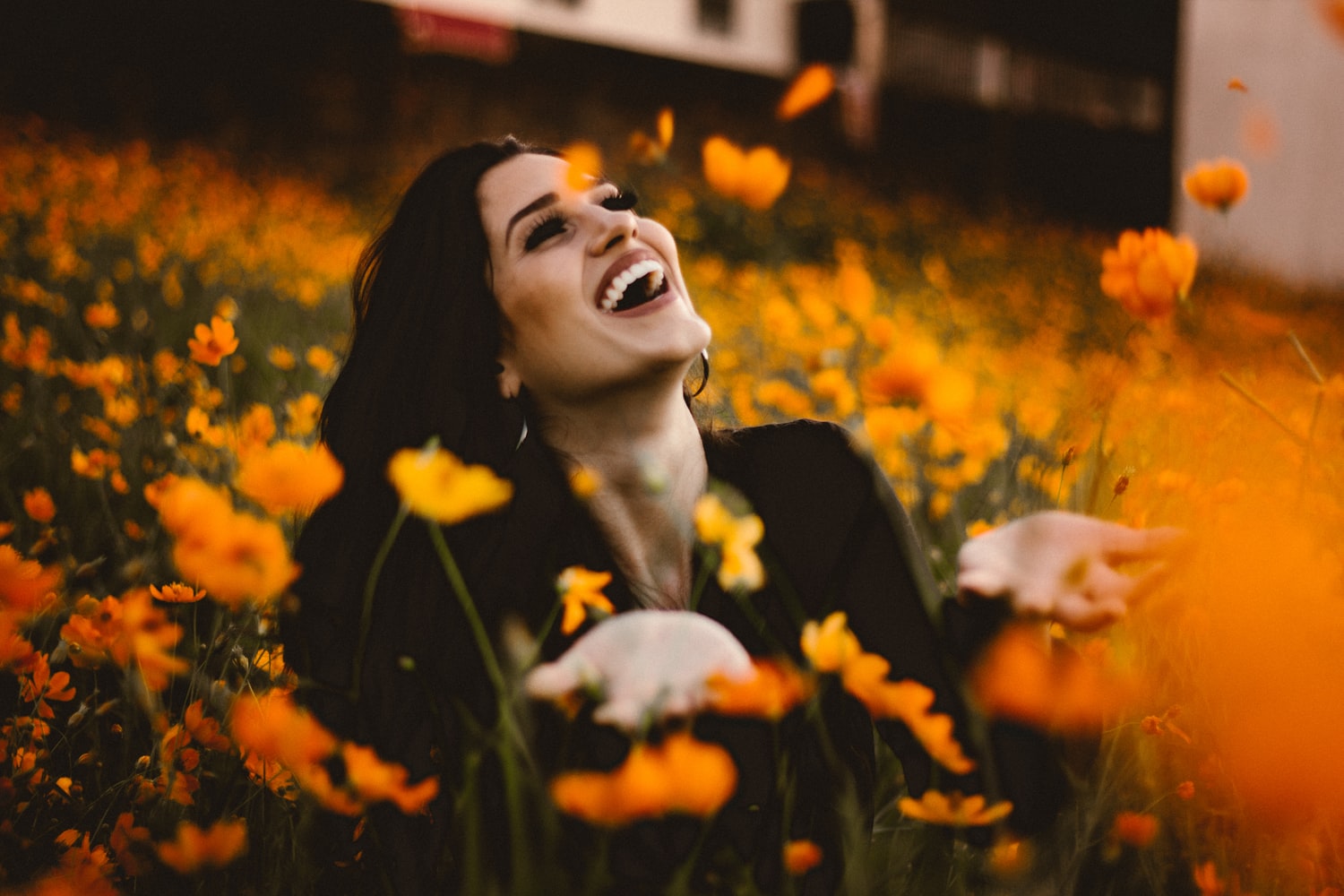 a woman surrounded by  yellow flowers laughing